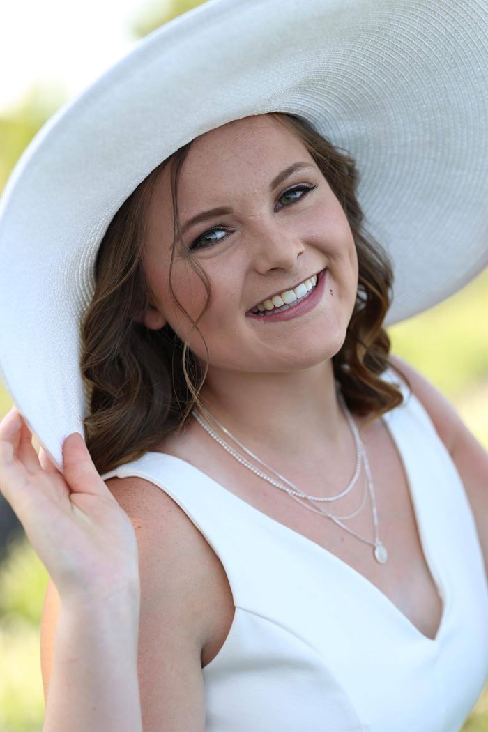 A before image of a woman in a large white hat and dress.