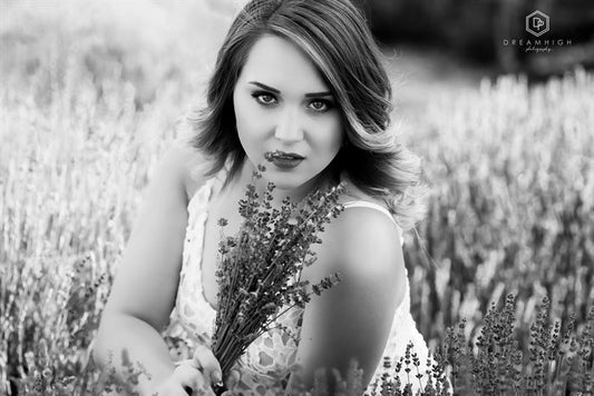 A black and white image of a young woman sitting in a lavender field edited with Pure Soft and Airy Photoshop Actions and Lightroom Presets.