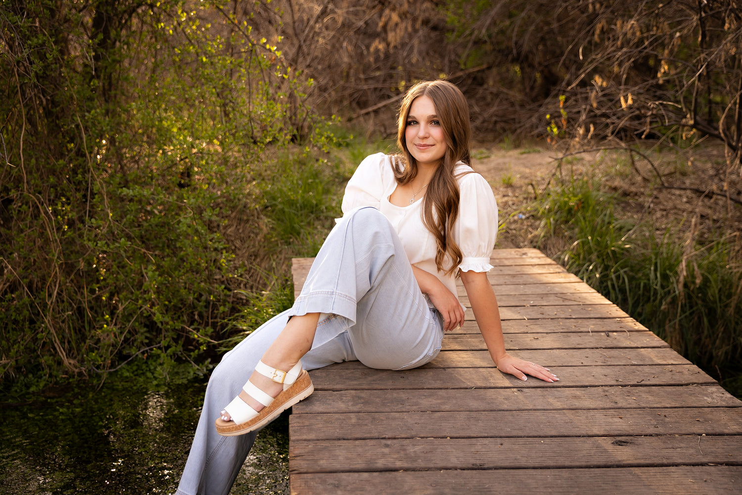 Woman sitting on a wooden dock in a natural setting