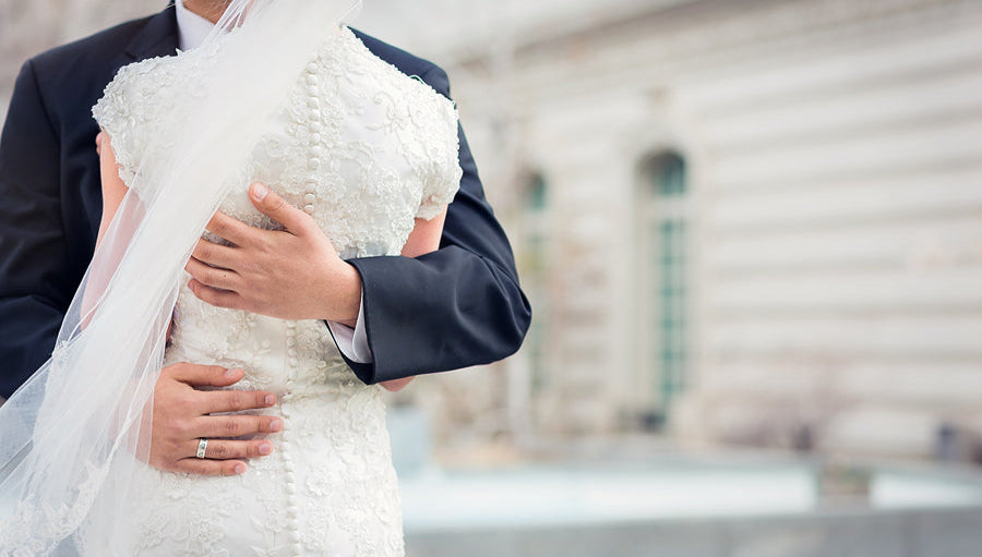 A bride and groom with the button details of the bride's dress in focus.  FAQ image.