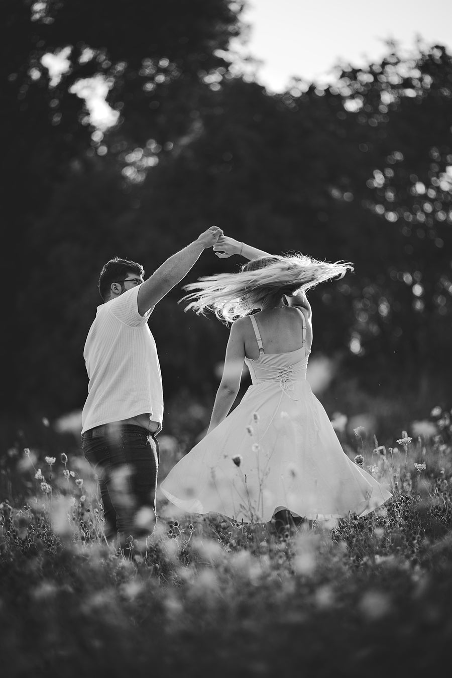 An image of a couple dancing in a field of wildflowers.  Edited with Pure Lightroom presets with a dramatic Black and white preset.