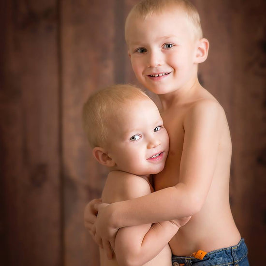 Two young boys hugging against a wood backdrop.  They are demonstrating the Pure Retouch photoshop technique.  