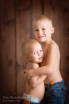 Two young boys hugging against a wood backdrop.  They are demonstrating the Pure Retouch photoshop technique.  