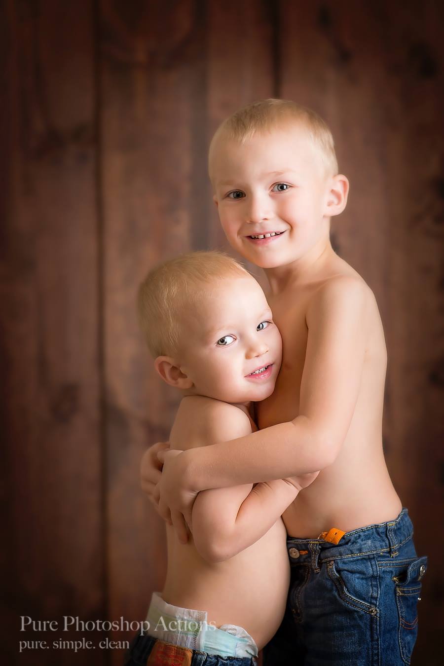 Two young boys hugging against a wood backdrop.  They are demonstrating the Pure Retouch photoshop technique.  
