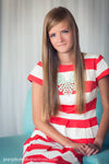 A young woman in a striped dress sitting in a blue chair against a white curtain demonstrating the Pure Retouch technique with creamy, flawless skin.