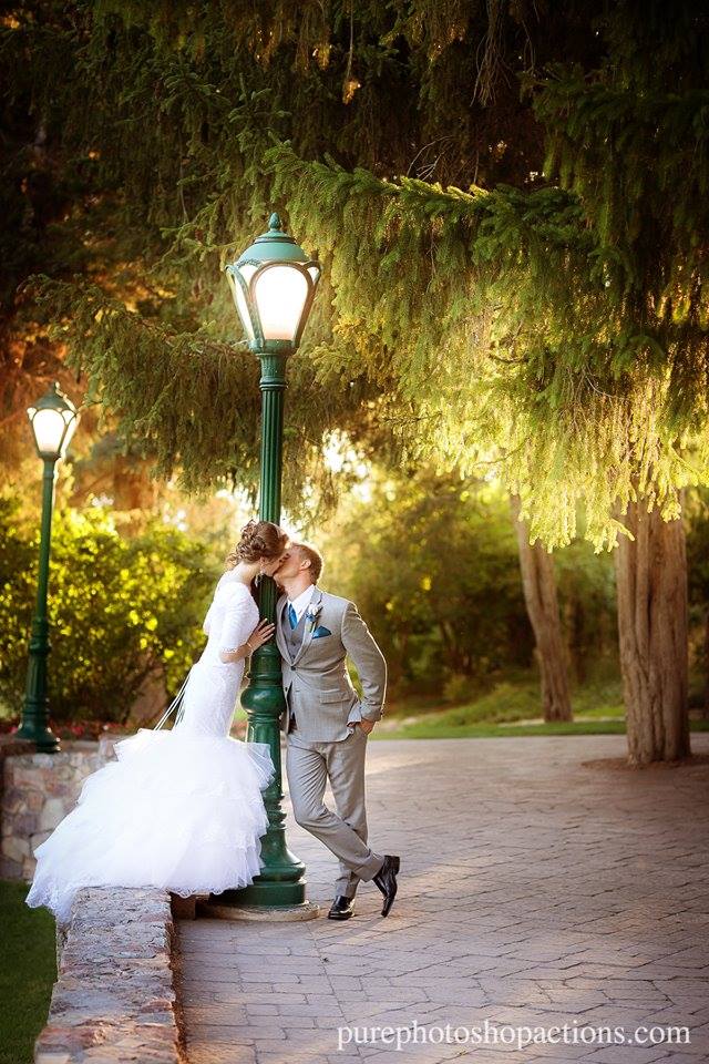An image of a bride and groom kissing in front of a green street light and drooping trees edited using Pure Essential Edit Photoshop Actions and Lightroom Presets.