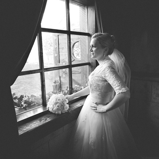 An image of a bride standing at an old fashioned window with her bouquet.  Edited using Pure Lightroom Presets Volume 1.
