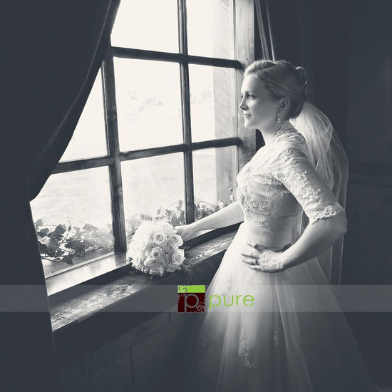 A bride standing in front of an old fashioned window with a cool matted black and white edit using Pure Split Tones Photoshop Actions set.