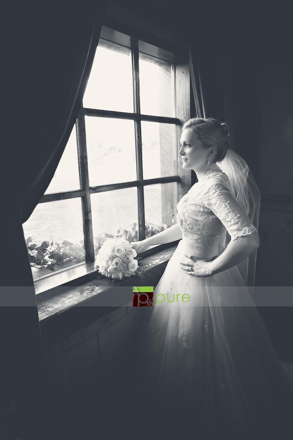 A bride standing in front of an old fashioned window with a cool matted black and white edit using Pure Split Tones Photoshop Actions set.