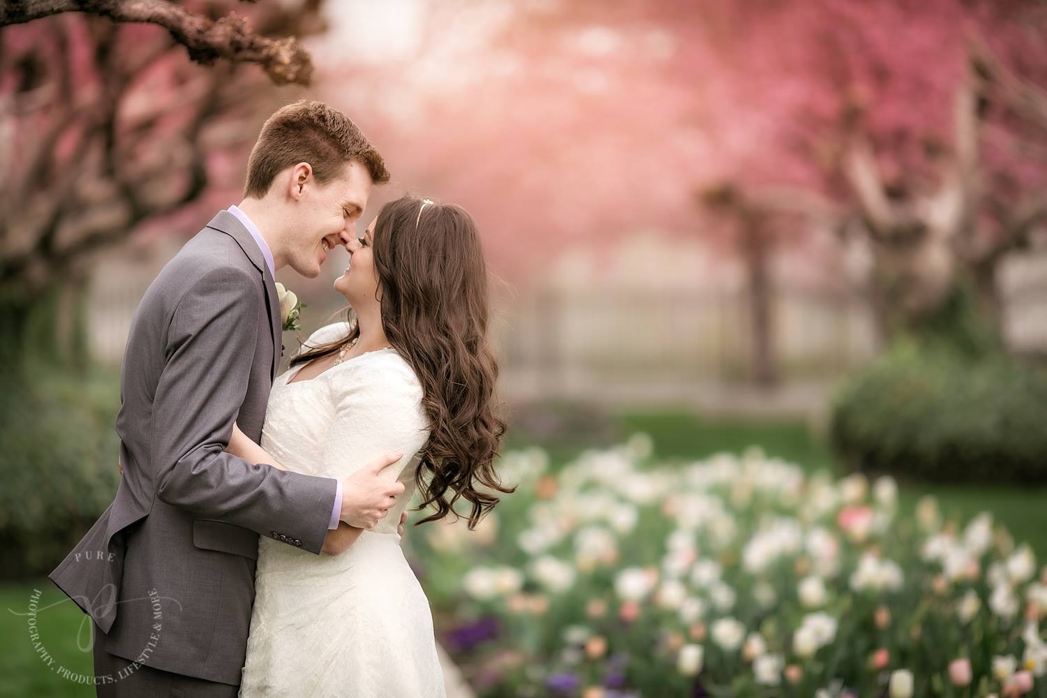 An image of a bride and groom among flowers and trees with pink blossoms, edited with Pure Lightroom Presets and Pure Photoshop Actions.